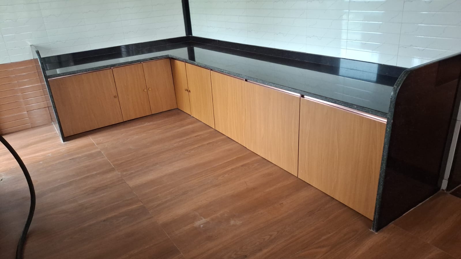 L-shaped kitchen counter with black granite top and wooden cabinets