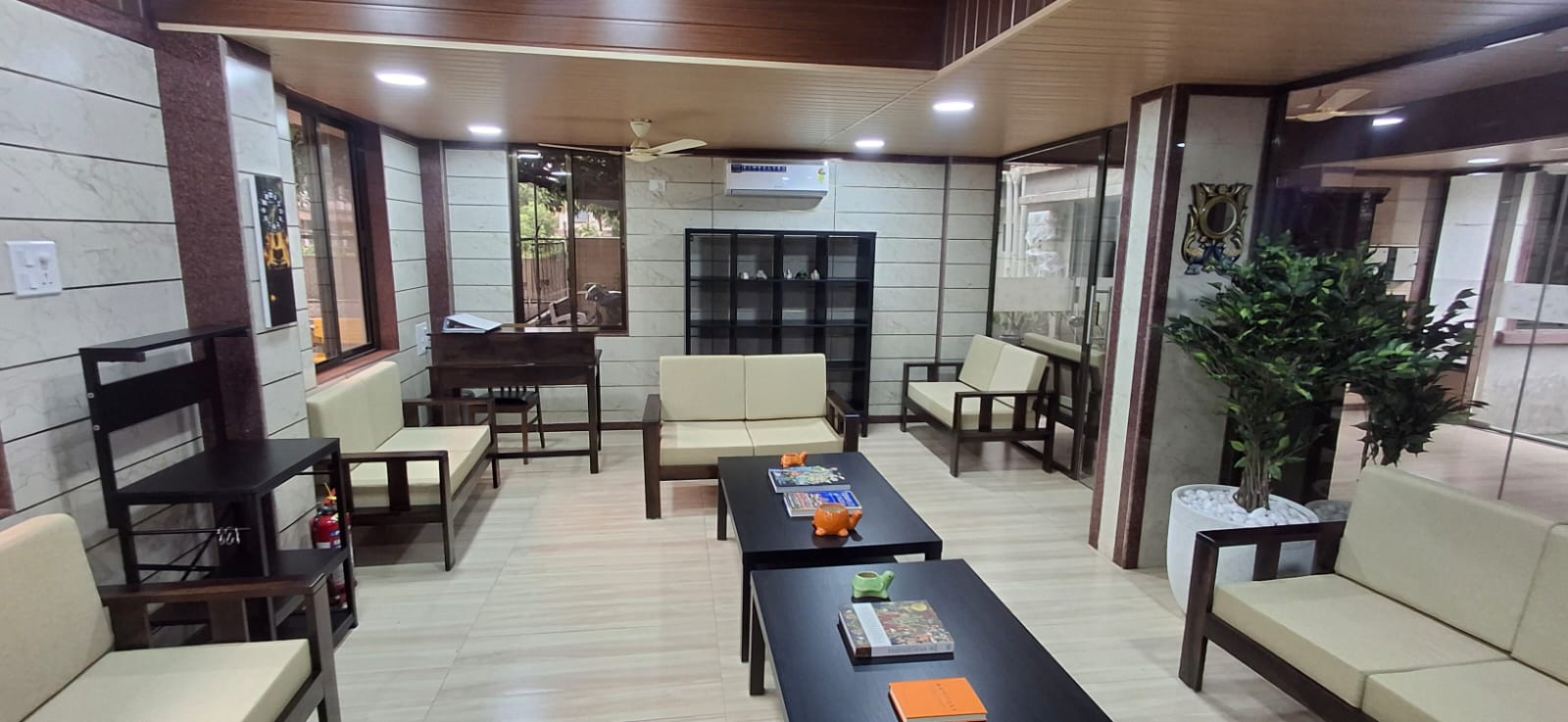 Library reading room with bookshelf, writing desk, sofas and indoor plants